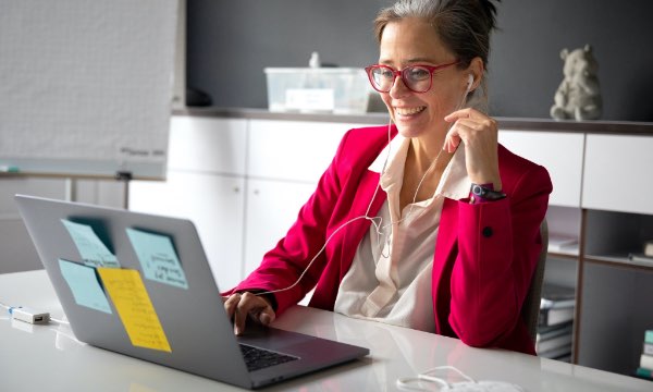 Frau sitzt am Laptop in einem Büro und nimmt an einer Video-Konferenz teil